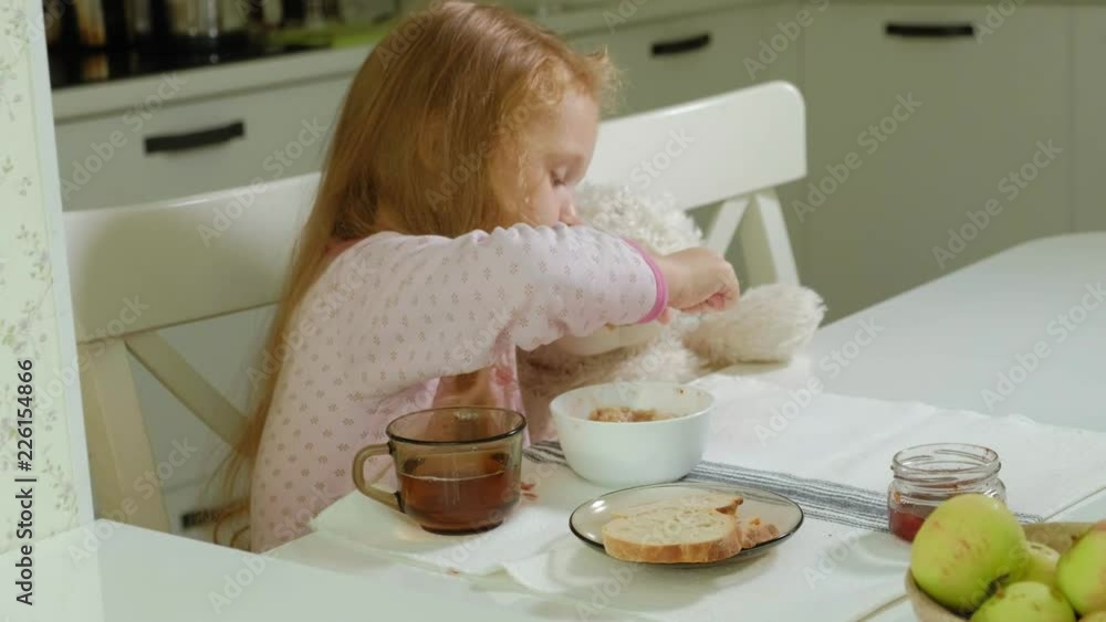 little girl eating porridge in the kitchen at home little girl eating porridge in the kitchen at home