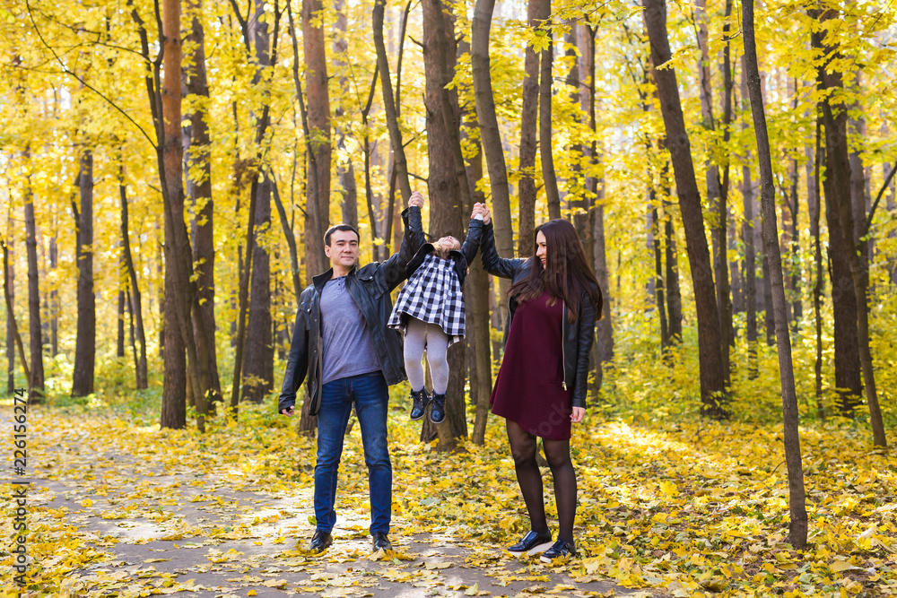 Fototapeta premium People, family and leisure concept - happy family with daughter walking in autumn park