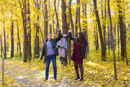 People, family and leisure concept - happy family with daughter walking in autumn park