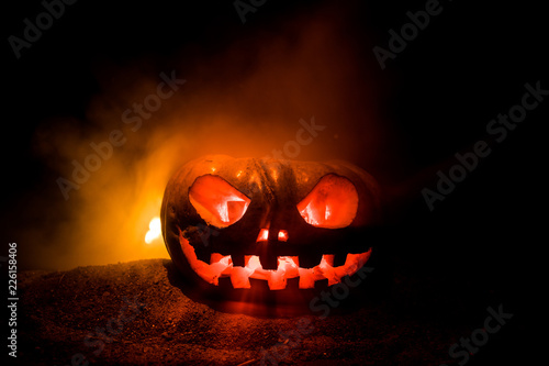 Halloween pumpkin smile and scrary eyes for party night. Close up view of scary Halloween pumpkin with eyes glowing inside at black background.