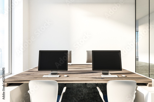Black computer screens on wooden office tables