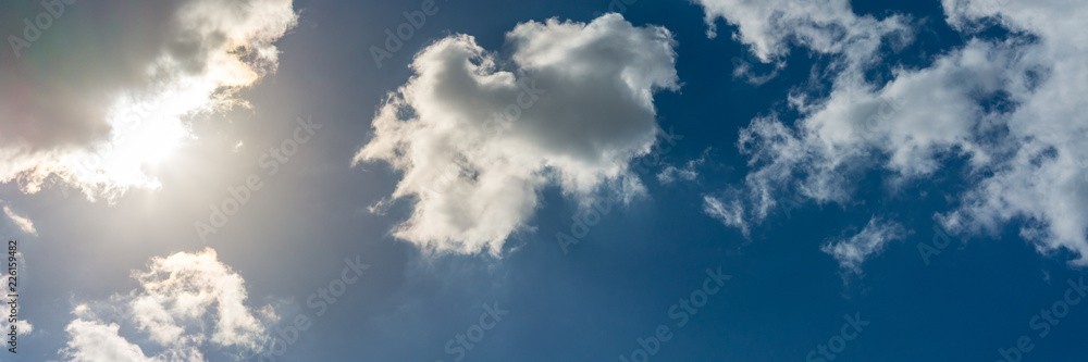 Fototapeta premium Sonnenschein bei blauem Himmel und Wolken, Panorama