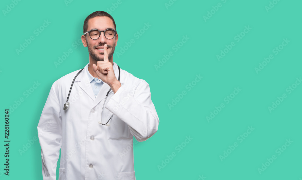Confident young doctor doing a gesture of silence Confident young doctor doing a gesture of silence