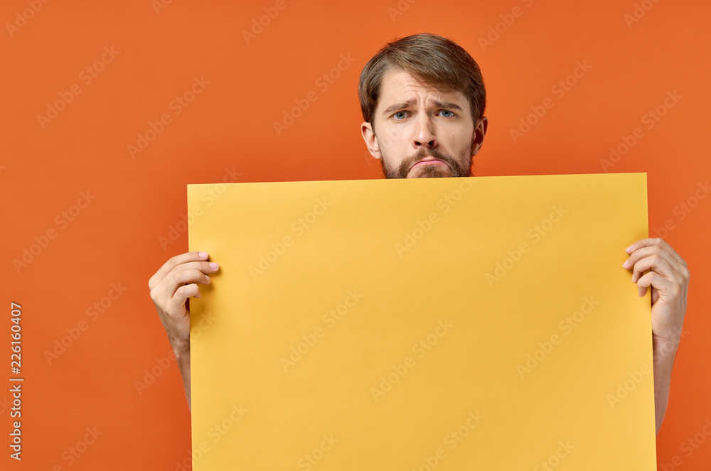 sad man holding a yellow sheet of paper on a red background, a free place sad man holding a yellow sheet of paper on a red background, a free place