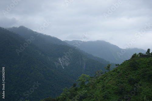mountain ranges with trees in forground clouds and blue sky