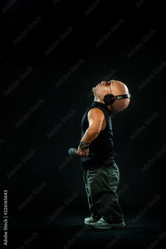 Portrait of stylish midget MC in with headphones and sunglasses posing with microphone. Portrait of stylish midget MC in with headphones and sunglasses posing with microphone.