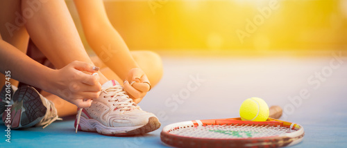 Tennis player tying shoelaces in court