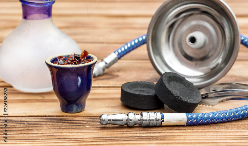 Hookah bowl with flavour tobacco and parts of hookah on wooden table. Hookah bowl with flavour tobacco and parts of hookah on wooden table.
