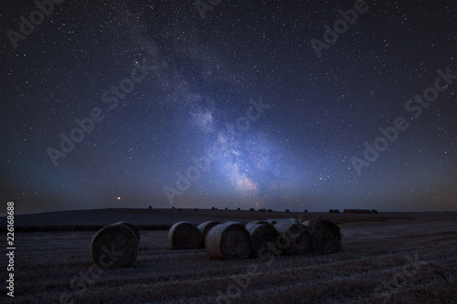 Vibrant Milky Way composite image over landscape of Lovely hay bales in English countryside