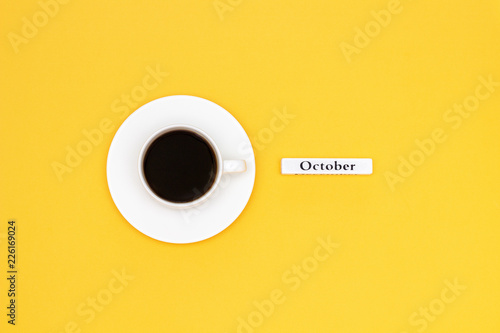 Cup of coffee and text October on yellow background