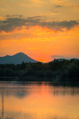 A beautiful  colorful sunset landscape with lake  mountain and forest. Natural evening scenery over the mountain lake in summer. Tatra mountains in Slovakia  Europe.