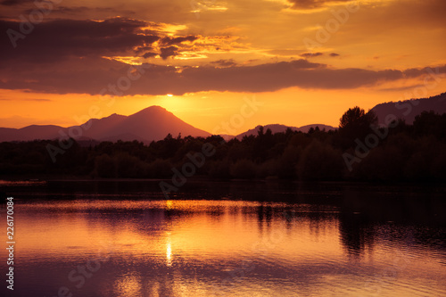 A beautiful, colorful sunset over the mountains, lake and forest in purple tones. Abstract, bright landscape. Tatra mountains in Slovakia, Europe.