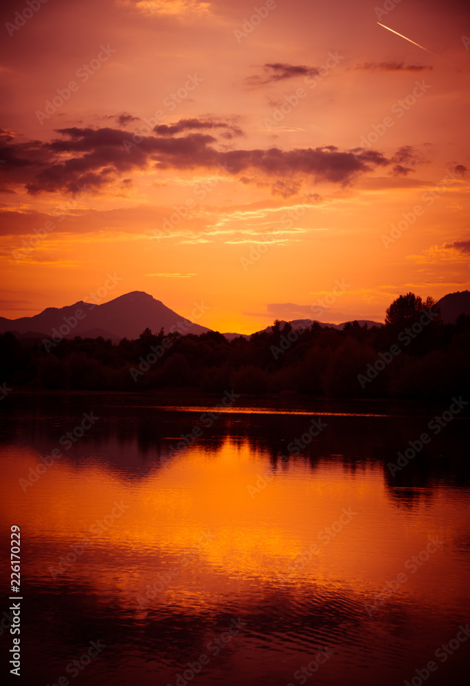 A beautiful, colorful sunset over the mountains, lake and forest in purple tones. Abstract, bright landscape. Tatra mountains in Slovakia, Europe.