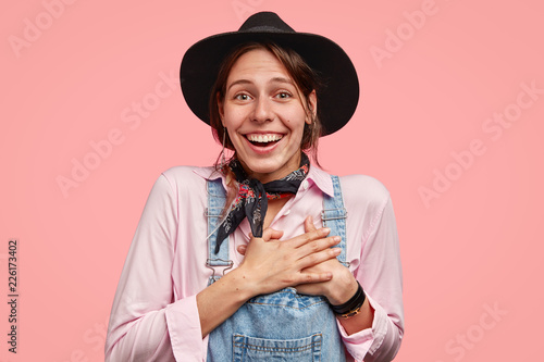 Photos Moved beautiful smiling gardener keeps both hands on heart, being pleased by pos