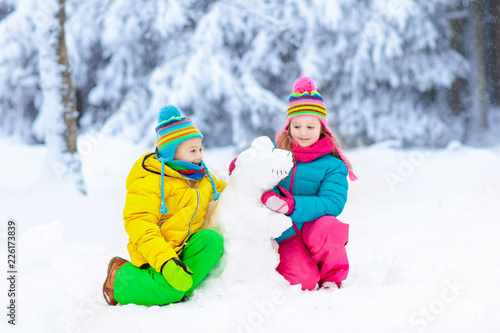 Kids making winter snowman. Children play in snow.