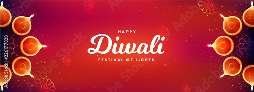 Top view of social media header or banner design decorated with illuminated oil lamps on glossy red background for Happy Diwali celebration.