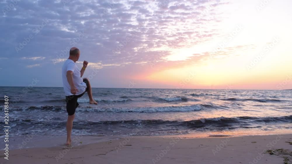 Adult sportsman warming up legs before exercising in the morning at sea Adult sportsman warming up legs before exercising in the morning at sea