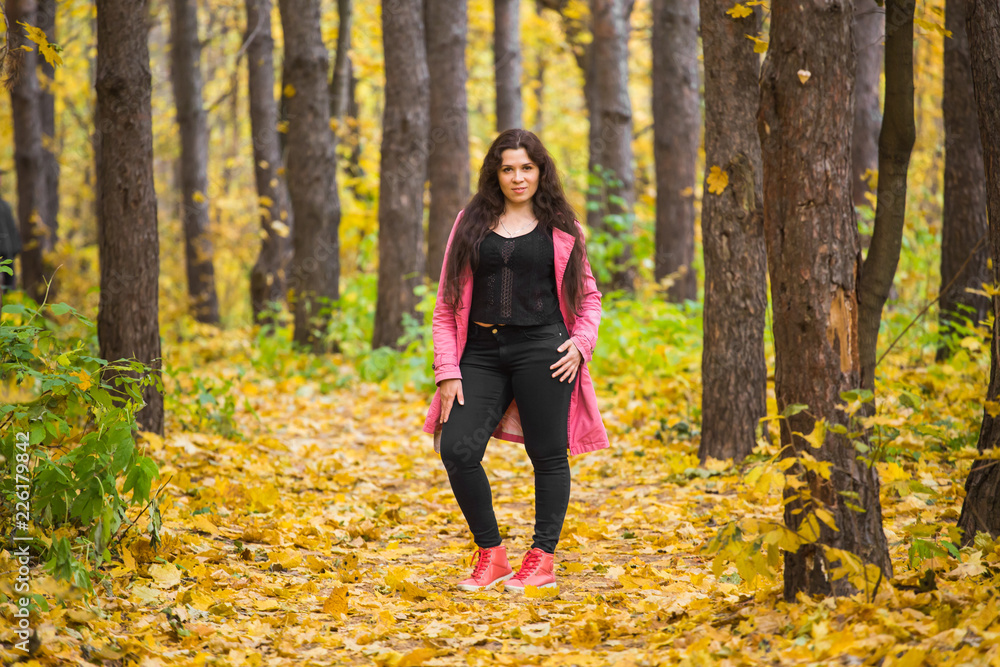 People, season and fashion concept - plus size woman walking in park in autumn People, season and fashion concept - plus size woman walking in park in autumn