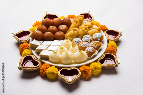 Diwali Rangoli made using Diya/oil lamp, flowers and plate full of Gulab Jamun, Rasgulla, kaju katli, morichoor / Bundi Laddu, Gujiya or Karanji  photo