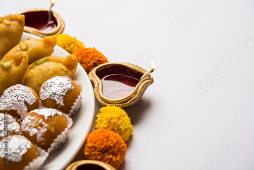 Diwali Rangoli made using Diya/oil lamp, flowers and plate full of Gulab Jamun, Rasgulla, kaju katli, morichoor / Bundi Laddu, Gujiya or Karanji  photo