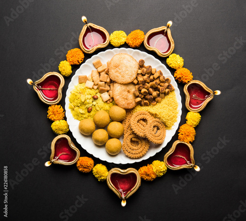 Diwali Rangoli or design made using Indian snacks/sweet and diya or lamp and flowers