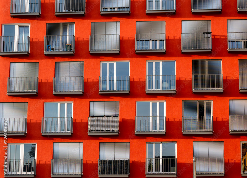 Image of red high rise building with windows and balconies and blinds