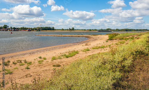 Panoramic image of the Dutch river Waal and the bank with planting on a warm day in the summer season