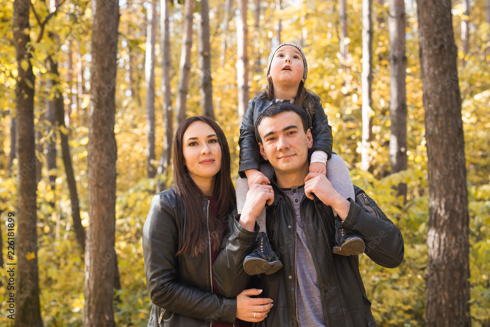Parenthood, fall and people concept - young family happy in autumn park Parenthood, fall and people concept - young family happy in autumn park