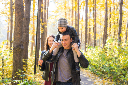 Fall, nature and family concept - happy family walking in autumn park