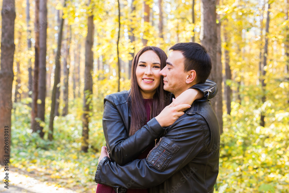 Cute couple outdoors in fall. Young man and woman in autumn nature Cute couple outdoors in fall. Young man and woman in autumn nature