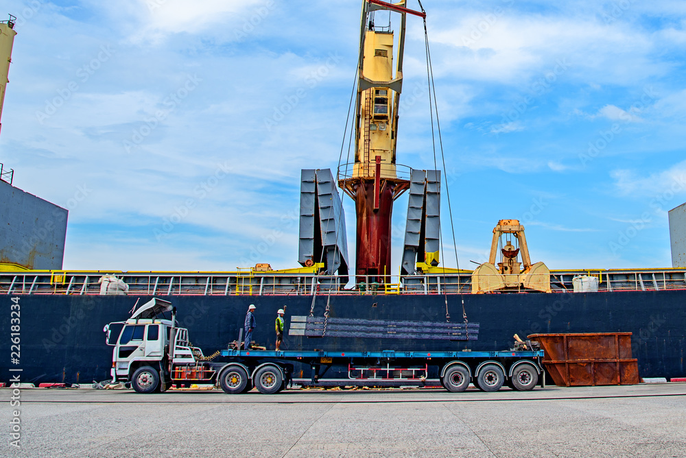 bundle of steel slab sheet being loading discharging in port terminal, handle by gang of stevedore labor , shipment cargo in transition from land and sea transport services. bundle of steel slab sheet being loading discharging in port terminal, handle by gang of stevedore labor , shipment cargo in transition from land and sea transport services.