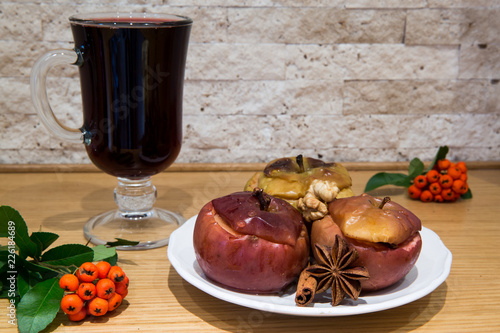 Hot mulled wine with low fat healthy dessert: baked apples with cinnamon and brown sugar, decorated with ashberry and pyracantha.