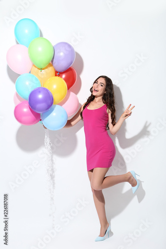 Young girl with colored balloons on white background
