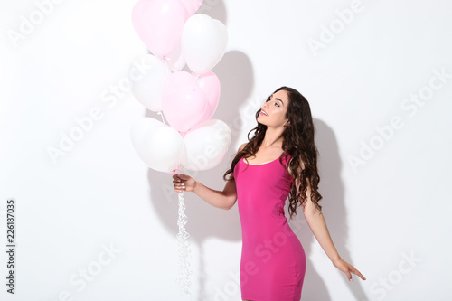 Beautiful girl with heart balloons on white background