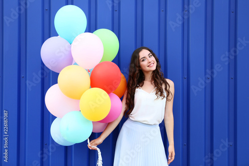Cute girl with colored balloons on blue background