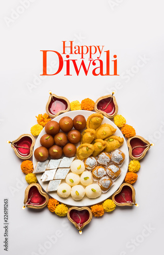 Happy Diwali Greeting Card made using sweets, or fire crackers or Diya or flowers, selective focus