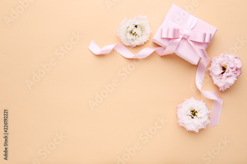 Gift box with ribbon and eustoma flowers on beige background © 5second