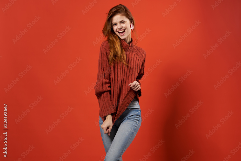 joyful woman in a warm sweater on a red background