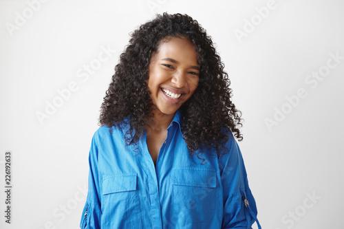 Genuine human facial expressions, emotions and feelings. Isolated picture of cheerful relaxed young dark skinned lady with dazzlign ultrawhite smile laughing at joke, posing isolated in studio