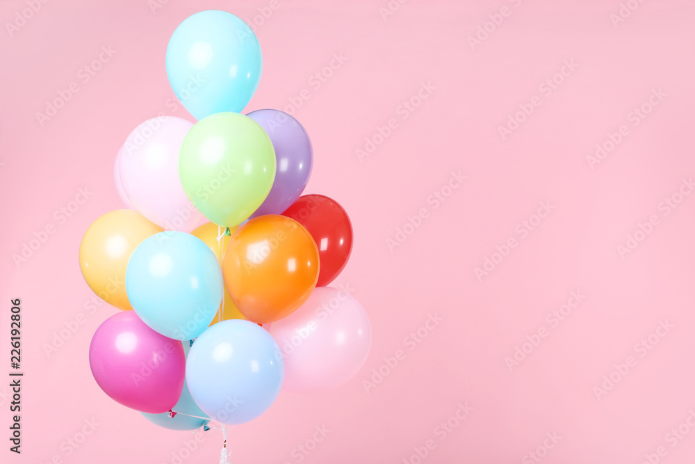 Colored balloons on pink background