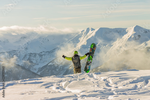 Snowboarder freerider is standing in the snowy mountains in winter under the clouds photo