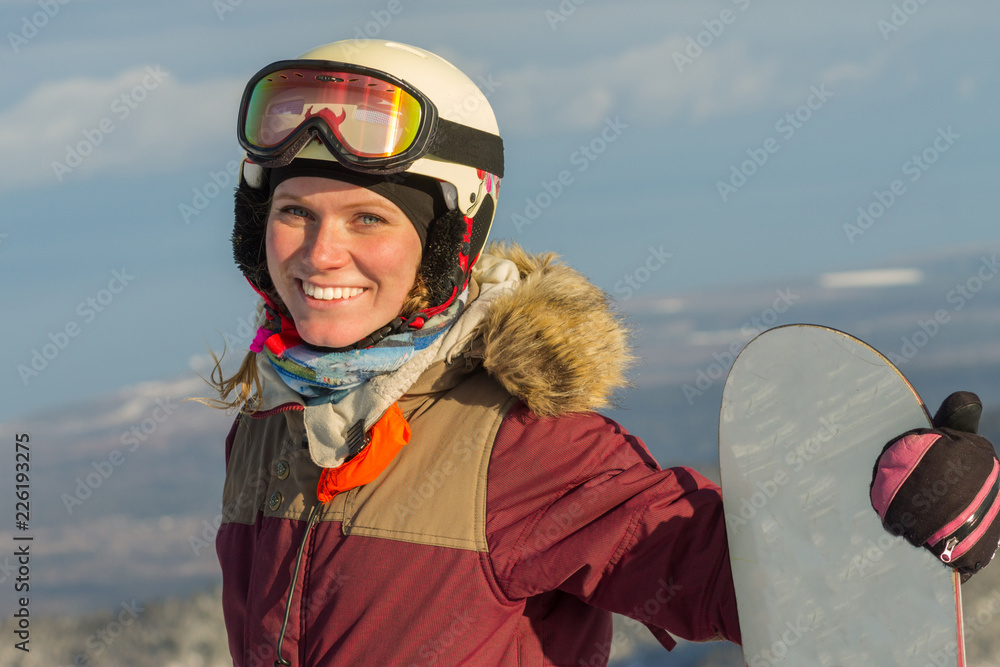 portrait of a snowboarder woman freerider in helmet in snowy mountains