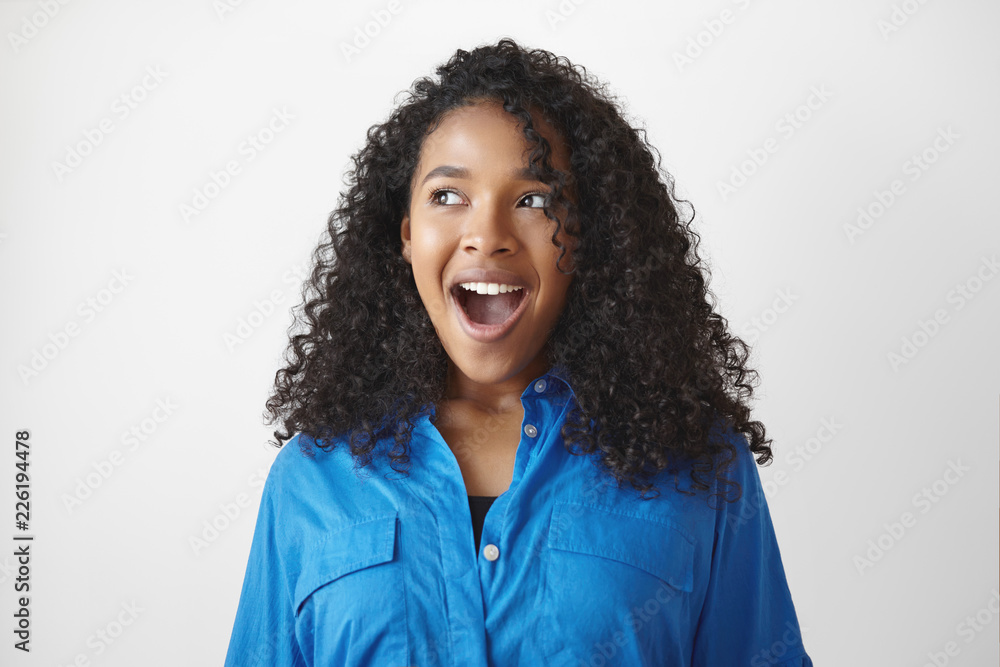Genuine human reactions and feelings. Isolated studio shot of gorgeous young dark skinned female opening mouth widely in excitement, having happy pleased expression, looking away in anticipation Genuine human reactions and feelings. Isolated studio shot of gorgeous young dark skinned female opening mouth widely in excitement, having happy pleased expression, looking away in anticipation