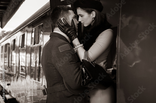 Foto Vintage couple embracing on railway station platform as train is about to depart