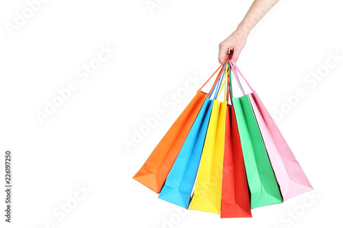 Female hand holding colorful shopping bags on white background