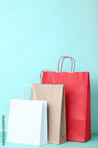Colorful paper shopping bags on mint background