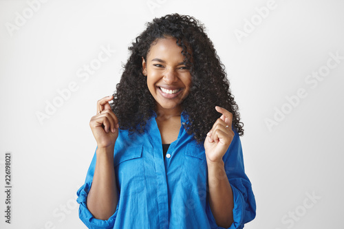 People, true emotions and feelings. Horizontal studio shot of cheerful beautiful young mixed race female with voluminous black hair expressing joy, feeling happy and excited, laughing out loud © shurkin_son
