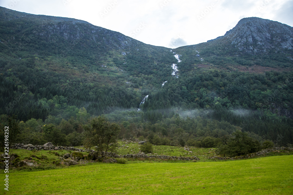 A beautiful green mountain valley near Rosendal in Norway. Autumn landscape in Folgefonna national park. Overcast day. A beautiful green mountain valley near Rosendal in Norway. Autumn landscape in Folgefonna national park. Overcast day.