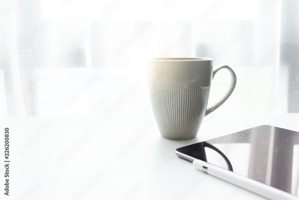 Coffee cup on white tablew with white window in the morning sunlight Coffee cup on white tablew with white window in the morning sunlight