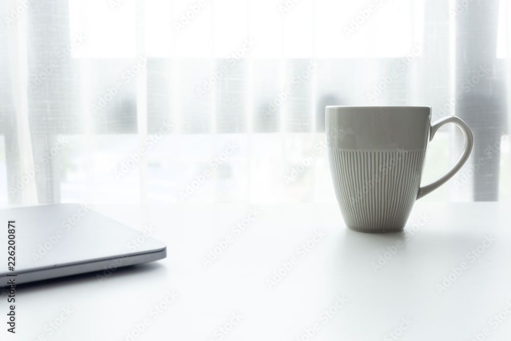 Coffee cup on white tablew with white window in the morning sunlight 